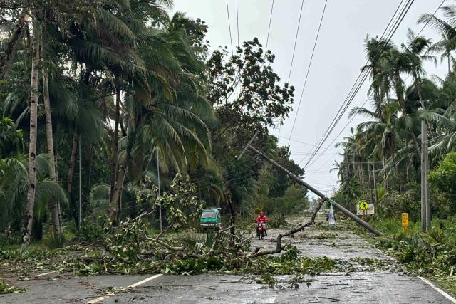 TOPSHOT - A motorist drives past a fallen electric post and trees on a highway in the aftermath of Typhoon Kalmaegi in Mayorga, Leyte province on November 4, 2025. Residents sought refuge on rooftops and cars floated through flooded streets on November 4 as Typhoon Kalmaegi battered the central Philippines, leaving at least two people dead. (Photo by AFP)