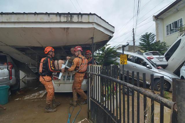 TOPSHOT - Rescuers evacuate a resident from their flood-hit home following heavy rains brought by Typhoon Kalmaegi in a subdivision of Cebu City in the central Philippines on November 4, 2025. Residents sought refuge on rooftops and cars floated through flooded streets on November 4 as Typhoon Kalmaegi battered the central Philippines, leaving at least two people dead. (Photo by Alan TANGCAWAN / AFP)
