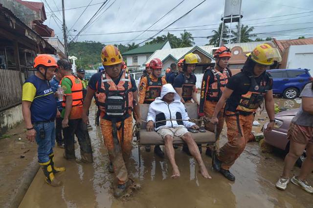 Rescuers evacuate a resident from their flood-hit home following heavy rains brought by Typhoon Kalmaegi in a subdivision of Cebu City in the central Philippines on November 4, 2025. Residents sought refuge on rooftops and cars floated through flooded streets on November 4 as Typhoon Kalmaegi battered the central Philippines, leaving at least two people dead. (Photo by Alan TANGCAWAN / AFP)