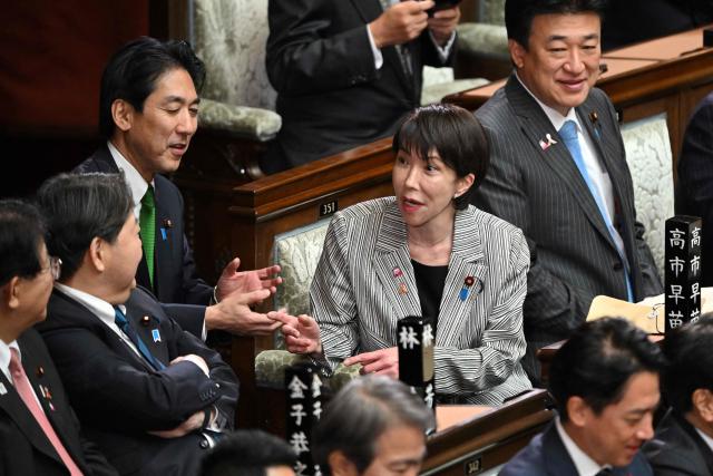 Japan's Prime Minister Sanae Takaichi (C) chats with her cabinet members before a session to answer questions from Yoshihiko Noda, leader of the main opposition Constitutional Democratic Party of Japan (CDP), regarding her policy speech at the House of Representatives of the National Diet in Tokyo on November 4, 2025. (Photo by Kazuhiro NOGI / AFP)