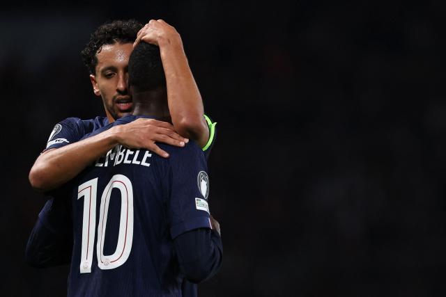 Paris Saint-Germain's Brazilian defender #05 Marquinhos (L) cheers Paris Saint-Germain's French forward #10 Ousmane Dembele who scored a goal which was later disallowed after a VAR review during the UEFA Champions League, league phase day 4, football match between Paris Saint-Germain (PSG) and FC Bayern Munich at the Parc des Princes in Paris, on November 4, 2025. (Photo by Anne-Christine POUJOULAT / AFP)