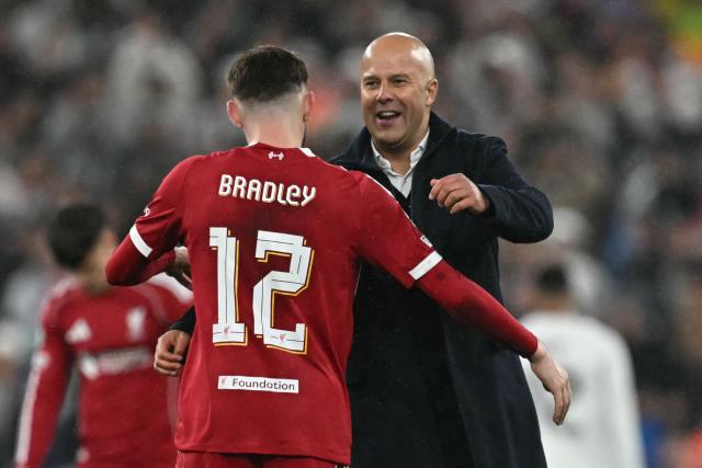 Liverpool's Dutch manager Arne Slot (R) congratulates Liverpool's Northern Irish defender #12 Conor Bradley (L) on the pitch after the UEFA Champions League, league phase football match between Liverpool and Real Madrid at Anfield in Liverpool, north west England on November 4, 2025. Liverpool won the game 1-0. (Photo by Paul ELLIS / AFP)