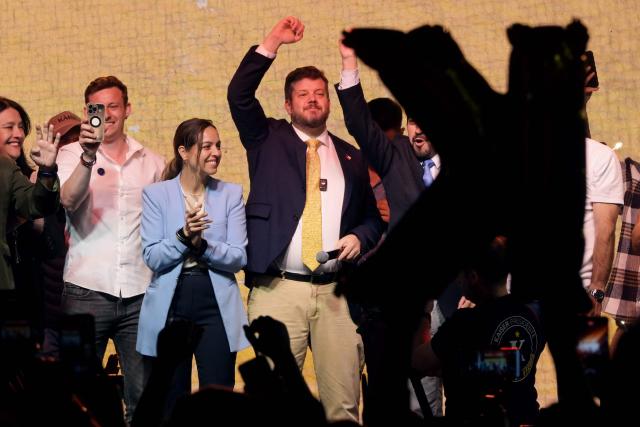 Chile's presidential candidate Johannes Kaiser (C) of the Libertarian National party, waves to supporters next to his wife, Ivette Avaria Vera, during a rally after a national tour, in Santiago on November 4, 2025. Chile will hold the presidential election on November 16, 2025. (Photo by RODRIGO ARANGUA / AFP)