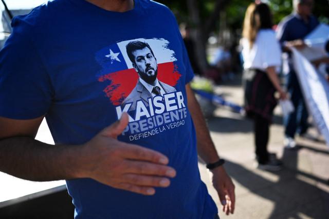 A supporter of Chile's presidential candidate Johannes Kaiser, of the Libertarian National party, shows a t-shirt depicting the candidate as he waits for his arrival to a rally after a national tour, in Santiago on November 4, 2025. Chile will hold the presidential election on November 16, 2025. (Photo by RODRIGO ARANGUA / AFP)