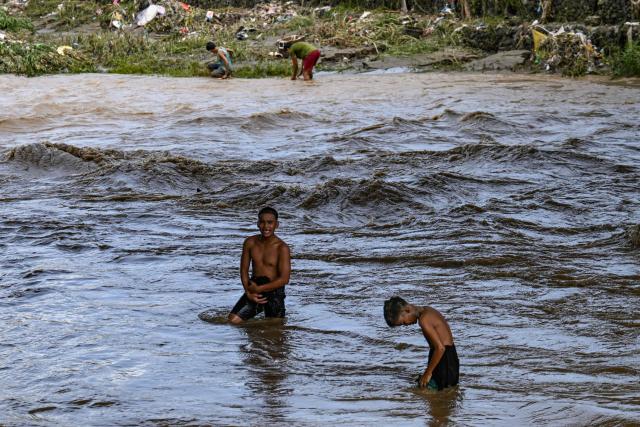 Residents wash themselves in the river in the aftermath of Typhoon Kalmaegi in Talisay, in the province of Cebu on November 5, 2025. (Photo by Jam STA ROSA / AFP)