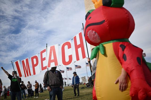 Demonstrators carry a sign reading "IMPEACH" during the kick off event for a "Trump Must Go" protest near the Washington Monument in Washington, DC, on November 5, 2025, marking the first anniversary of Donald Trump’s election to a second term. (Photo by ANDREW CABALLERO-REYNOLDS / AFP)
