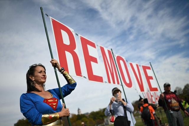 Demonstrators carry a sign reading "REMOVE" during the kick off event for a "Trump Must Go" protest near the Washington Monument in Washington, DC, on November 5, 2025, marking the first anniversary of Donald Trump’s election to a second term. (Photo by ANDREW CABALLERO-REYNOLDS / AFP)