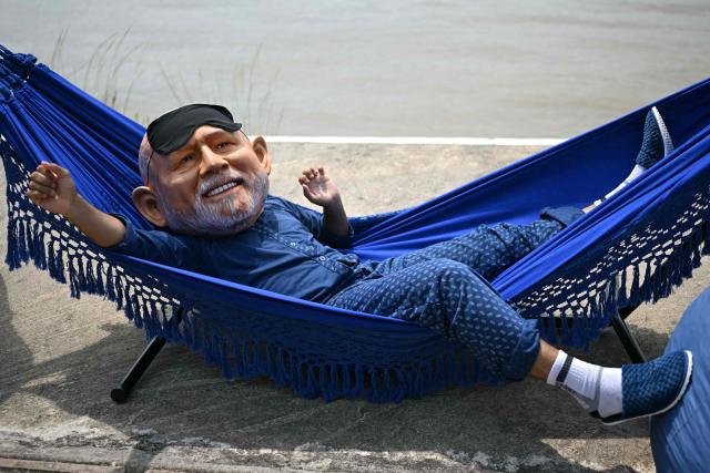 An Oxfam activist wearing an oversized mask representing Brazil's President Luiz Inacio Lula da Silva poses during their "Big Heads" protest stunt at the riverbank of the Federal University of Para (Orla da UFPA), Belem, Brazil, on November 5, 2025 on the sidelines of the COP30 UN Climate Summit. (Photo by Mauro PIMENTEL / AFP)