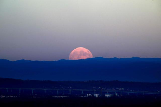 The full moon, known as Beaver Moon, rises over a highway bridge near the city of Lyon, on November 5,2025. (Photo by OLIVIER CHASSIGNOLE / AFP)