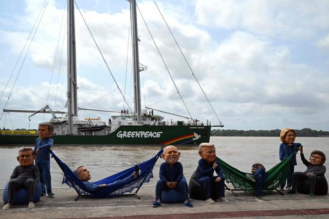 Oxfam activists wearing oversized masks representing (L to R) Britain's Prime Minister Keir Starmer, France's President Emmanuel Macron, Canada's Prime Minister Mark Carney, Brazil's President Luiz Inacio Lula da Silva, US President Donald Trump, South Africa's President Cyril Ramaphosa, European Commission President Ursula Von der Leyen and Argentina's President Javier Milei pose during their “Big Heads” protest at the riverbank of the Federal University of Parб (Orla da UFPA), with Greenpeace’s Rainbow Warrior ship in the background, in Belem, Para state, Brazil, on November 5, 2025, on the sidelines of the COP30 UN Climate Summit. (Photo by Mauro PIMENTEL / AFP)