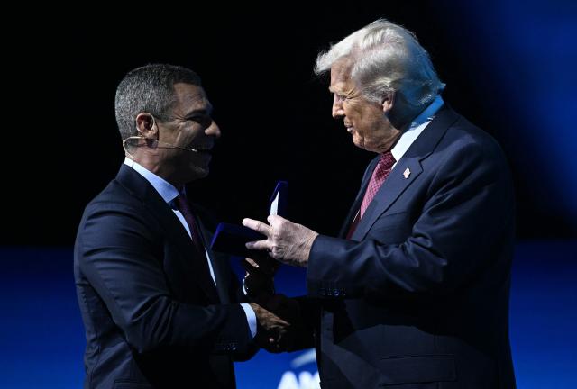 US President Donald Trump accepts a "key to the city" from Miami Mayor Francis Suarez at the American Business Forum at the Kaseya Center in Miami on November 5, 2025. (Photo by Brendan SMIALOWSKI / AFP)
