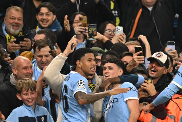 Manchester City's English midfielder #47 Phil Foden is mobbed by teammates after scoring the team's first goal during the UEFA Champions League football match between Manchester City and Borussia Dortmund at the Etihad Stadium in Manchester, north west England, on November 5, 2025. (Photo by Oli SCARFF / AFP)