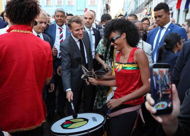 France's President Emmanuel Macron plays a drum alongside musicians during a visit to the historic Pelourinho district in Salvador, in Brazil's Bahia state, on November 5, 2025. (Photo by Ludovic MARIN / AFP)