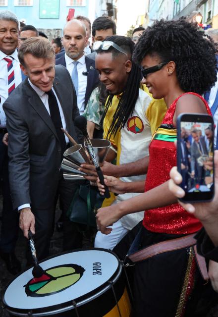 France's President Emmanuel Macron plays a drum alongside musicians during a visit to the historic Pelourinho district in Salvador, in Brazil's Bahia state, on November 5, 2025. (Photo by Ludovic MARIN / AFP)