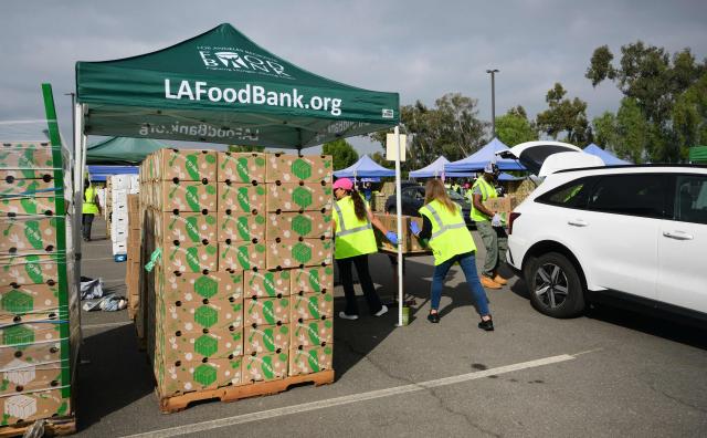 People receive free food from the Los Angeles Regional Food Bank on November 5, 2025, in City of Industry, California, as the donations are loaded into their trunks. The US government shutdown became the longest ever on November 5, 2025, topping the 35-day record set during Donald Trump's first term, as his administration warned of holiday air travel chaos and threatened Americans' benefits in a bid to force a resolution. (Photo by Frederic J. BROWN / AFP)