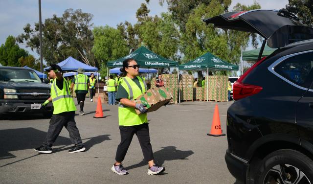 People receive free food from the Los Angeles Regional Food Bank on November 5, 2025, in City of Industry, California, as the donations are loaded into their trunks. The US government shutdown became the longest ever on November 5, 2025, topping the 35-day record set during Donald Trump's first term, as his administration warned of holiday air travel chaos and threatened Americans' benefits in a bid to force a resolution. (Photo by Frederic J. BROWN / AFP)