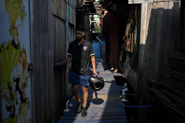 A man wearing a Sao Paulo's football team jersey walks through Vila da Barca, a neighborhood of stilt houses in Belem, Para State, Brazil on November 5, 2025. (Photo by Mauro PIMENTEL / AFP)