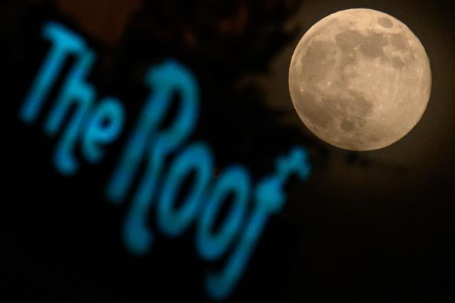 November's full moon, also known as Beaver Moon, is pictured by the sign of a coffee shop while it rises over Fort-de-France, in the French overseas island of Martinique, on November 5, 2025. (Photo by Loic VENANCE / AFP)