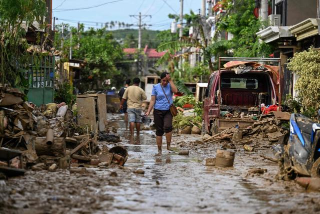 A woman walks along a mud covered street in the aftermath of Typhoon Kalmaegi in Liloan, in the province of Cebu on November 6, 2025. The death toll from Typhoon Kalmaegi in the central Philippines climbed past 100, as the devastating impact on Cebu province became clearer after the worst flooding in recent memory. (Photo by Jam STA ROSA / AFP)