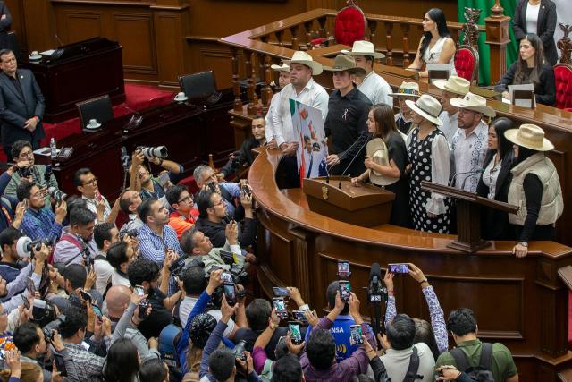 The widow of the late Mayor Carlos Manzo, Grecia Quiroz, accompanied by state representative Carlos Tafolla and Uruapan city officials, delivers a speech at the Michoacan State Congress after being sworn in as Mayor of Uruapan in Uruapan, Michoacan State, Mexico on November 5, 2025. The Mexican government reported on November 2 that the mayor of Uruapan, Carlos Manzo, who was killed the previous night during a public event in the western state of Michoacan, had been under official protection since December last year. (Photo by Enrique Castro / AFP)