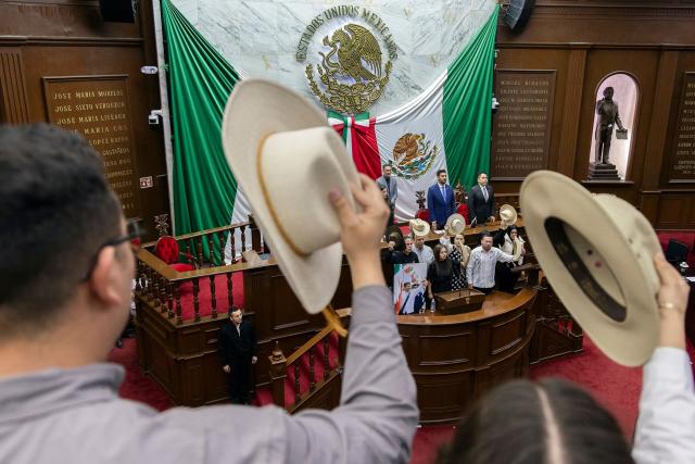 The widow of the late Mayor Carlos Manzo, Grecia Quiroz, accompanied by state representative Carlos Tafolla and Uruapan city officials, delivers a speech at the Michoacan State Congress after being sworn in as Mayor of Uruapan in Uruapan, Michoacan State, Mexico on November 5, 2025. The Mexican government reported on November 2 that the mayor of Uruapan, Carlos Manzo, who was killed the previous night during a public event in the western state of Michoacan, had been under official protection since December last year. (Photo by Enrique Castro / AFP)