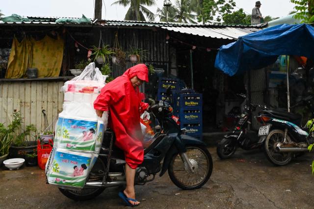 A woman stacks toilet paper on the back of her scooter as she prepares to leave her home temporarily for a safer location in Gia Lai province, central Vietnam on November 6, 2025, in anticipation of the arrival of typhoon Kalmaegi. The typhoon is forecast to make landfall in central Vietnam late on November 6, bringing waves as high as eight metres (26 feet) and powerful storm surges, according to the national weather bureau. (Photo by Nhac NGUYEN / AFP)