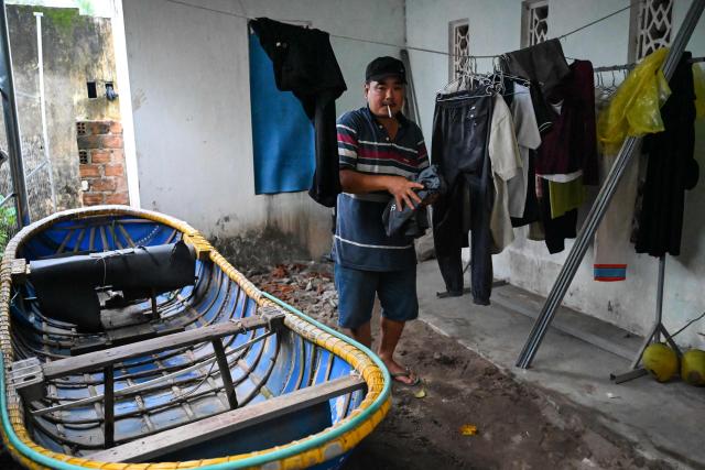 A man folds clothes as he prepares to leave his home temporarily for a safer location in Gia Lai province, central Vietnam on November 6, 2025, in anticipation of the arrival of typhoon Kalmaegi. The typhoon is forecast to make landfall in central Vietnam late on November 6, bringing waves as high as eight metres (26 feet) and powerful storm surges, according to the national weather bureau. (Photo by Nhac NGUYEN / AFP)