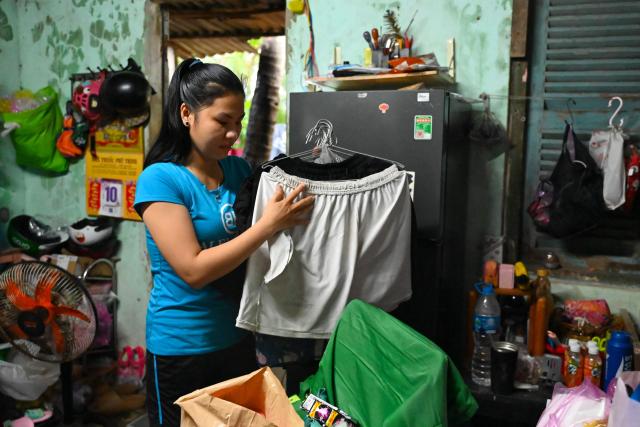 A woman folds clothes as she prepares to leave her home temporarily for a safer location in Gia Lai province, central Vietnam on November 6, 2025, in anticipation of the arrival of typhoon Kalmaegi. The typhoon is forecast to make landfall in central Vietnam late on November 6, bringing waves as high as eight metres (26 feet) and powerful storm surges, according to the national weather bureau. (Photo by NHAC NGUYEN / AFP)
