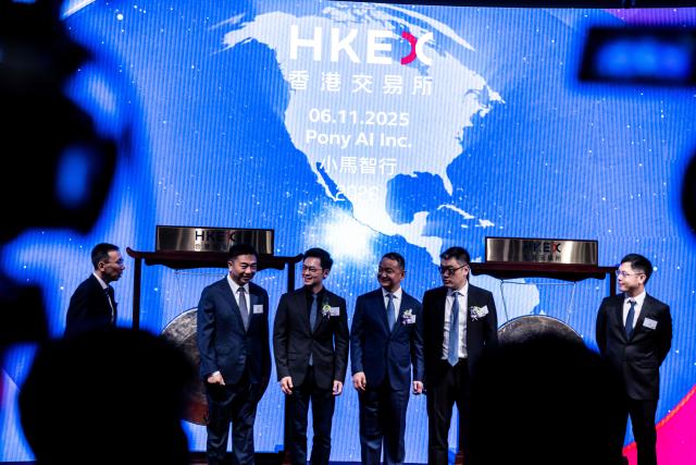 People attend the initial public offering (IPO) launch of Pony.AI and WeRide at the Hong Kong Stock Exchange on November 6, 2025. Shares in Chinese self-driving start-ups Pony.AI and WeRide falls on their first listing day in Hong Kong, as experts warns China has not fully ready to deploy a mass rollout of robotaxis due to regulatory changes. (Photo by ISAAC LAWRENCE / AFP)