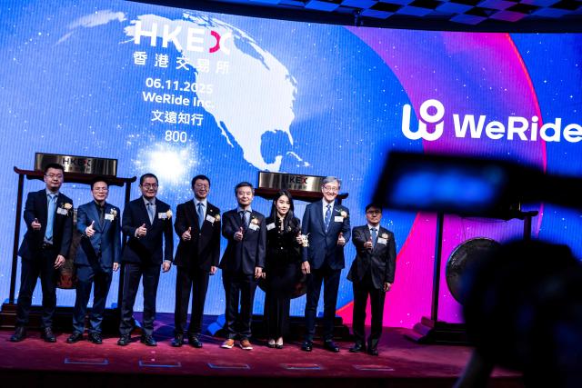 People attend the initial public offering (IPO) launch of Pony.AI and WeRide at the Hong Kong Stock Exchange on November 6, 2025. Shares in Chinese self-driving start-ups Pony.AI and WeRide falls on their first listing day in Hong Kong, as experts warns China has not fully ready to deploy a mass rollout of robotaxis due to regulatory changes. (Photo by ISAAC LAWRENCE / AFP)