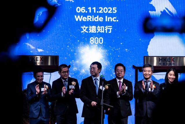 People attend the initial public offering (IPO) launch of Pony.AI and WeRide at the Hong Kong Stock Exchange on November 6, 2025. Shares in Chinese self-driving start-ups Pony.AI and WeRide falls on their first listing day in Hong Kong, as experts warns China has not fully ready to deploy a mass rollout of robotaxis due to regulatory changes. (Photo by ISAAC LAWRENCE / AFP)