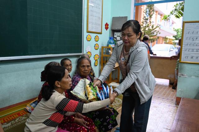 Snacks are offered to people, seeking temporary shelter from the incoming typhoon Kalmaegi, in a primary school in Gia Lai province, central Vietnam on November 6, 2025. The typhoon is forecast to make landfall in central Vietnam late on November 6, bringing waves as high as eight metres (26 feet) and powerful storm surges, according to the national weather bureau. (Photo by NHAC NGUYEN / AFP)