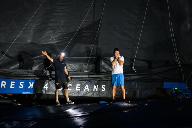 "SVR-LAZARTIGUE" ULTIM class multihull French skippers Franck Cammas (L) and Tom Laperche, celebrate while crossing the finish line to win the 17th edition of the Transat Cafe L'Or, off the shores of Fort-de-France, in the French overseas island of Martinique on November 5, 2025. Four open classes will take part in the race: IMOCA, Ocean Fifty, ULTIM and Class40. The Transat Cafe L'Or is a duo sailing race from Le Havre to Fort-de-France, in the French Caribbean island of Martinique. (Photo by Loic VENANCE / AFP)