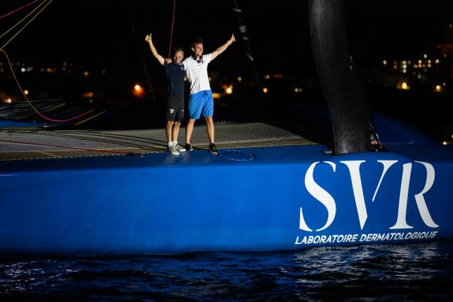 "SVR-LAZARTIGUE" ULTIM class multihull French skippers Franck Cammas (L) and Tom Laperche, celebrate while crossing the finish line to win the 17th edition of the Transat Cafe L'Or, off the shores of Fort-de-France, in the French overseas island of Martinique on November 5, 2025. Four open classes will take part in the race: IMOCA, Ocean Fifty, ULTIM and Class40. The Transat Cafe L'Or is a duo sailing race from Le Havre to Fort-de-France, in the French Caribbean island of Martinique. (Photo by Loic VENANCE / AFP)