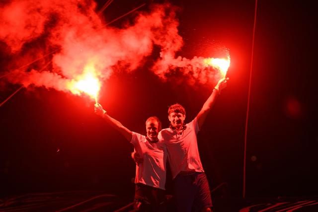 "SVR-LAZARTIGUE" ULTIM class multihull French skippers Franck Cammas (L) and Tom Laperche, celebrate with flares after crossing the finish line to win the 17th edition of the Transat Cafe L'Or, off the shores of Fort-de-France, in the French overseas island of Martinique on November 5, 2025. Four open classes will take part in the race: IMOCA, Ocean Fifty, ULTIM and Class40. The Transat Cafe L'Or is a duo sailing race from Le Havre to Fort-de-France, in the French Caribbean island of Martinique. (Photo by Loic VENANCE / AFP)