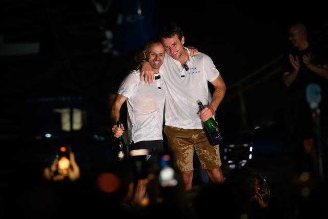 "SVR-LAZARTIGUE" ULTIM class multihull French skippers Franck Cammas (L) and Tom Laperche, celebrate on the pear after winning the 17th edition of the Transat Cafe L'Or, off the shores of Fort-de-France, in the French overseas island of Martinique on November 5, 2025. Four open classes will take part in the race: IMOCA, Ocean Fifty, ULTIM and Class40. The Transat Cafe L'Or is a duo sailing race from Le Havre to Fort-de-France, in the French Caribbean island of Martinique. (Photo by Loic VENANCE / AFP)