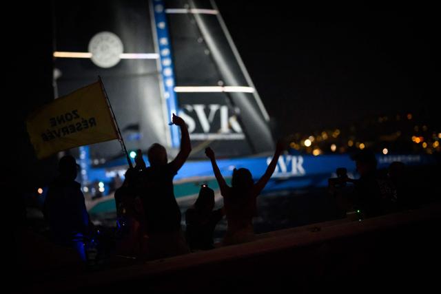 People celebrate on a boat as "SVR-LAZARTIGUE" ULTIM class multihull French skippers Franck Cammas and Tom Laperche, cross the finish line to win the 17th edition of the Transat Cafe L'Or, off the shores of Fort-de-France, in the French overseas island of Martinique on November 5, 2025. Four open classes will take part in the race: IMOCA, Ocean Fifty, ULTIM and Class40. The Transat Cafe L'Or is a duo sailing race from Le Havre to Fort-de-France, in the French Caribbean island of Martinique. (Photo by Loic VENANCE / AFP)
