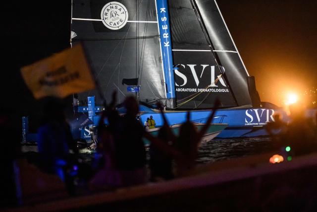 People celebrate on a boat as "SVR-LAZARTIGUE" ULTIM class multihull French skippers Franck Cammas and Tom Laperche, cross the finish line to win the 17th edition of the Transat Cafe L'Or, off the shores of Fort-de-France, in the French overseas island of Martinique on November 5, 2025. Four open classes will take part in the race: IMOCA, Ocean Fifty, ULTIM and Class40. The Transat Cafe L'Or is a duo sailing race from Le Havre to Fort-de-France, in the French Caribbean island of Martinique. (Photo by Loic VENANCE / AFP)