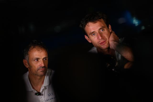 People celebrate on a boat as "SVR-LAZARTIGUE" ULTIM class multihull French skippers Franck Cammas (L) and Tom Laperche, answer journalists after winning the 17th edition of the Transat Cafe L'Or, off the shores of Fort-de-France, in the French overseas island of Martinique on November 5, 2025. Four open classes will take part in the race: IMOCA, Ocean Fifty, ULTIM and Class40. The Transat Cafe L'Or is a duo sailing race from Le Havre to Fort-de-France, in the French Caribbean island of Martinique. (Photo by Loic VENANCE / AFP)