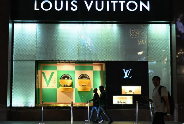 People walk past the French luxury brand Louis Vuitton store in Bengaluru on November 5, 2025. (Photo by Idrees MOHAMMED / AFP)