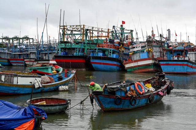 A man anchors a boat to protect it from the impact of Typhoon Kalmaegi at Quy Nhon fishing port in Gia Lai province in central Vietnam on November 6, 2025. The typhoon is forecast to make landfall in central Vietnam late on November 6, bringing waves as high as eight metres (26 feet) and powerful storm surges, according to the national weather bureau. (Photo by Nhac NGUYEN / AFP)