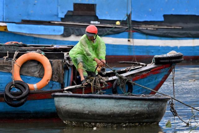 A man anchors a boat to protect it from the impact of Typhoon Kalmaegi at Quy Nhon fishing port in Gia Lai province in central Vietnam on November 6, 2025. The typhoon is forecast to make landfall in central Vietnam late on November 6, bringing waves as high as eight metres (26 feet) and powerful storm surges, according to the national weather bureau. (Photo by Nhac NGUYEN / AFP)