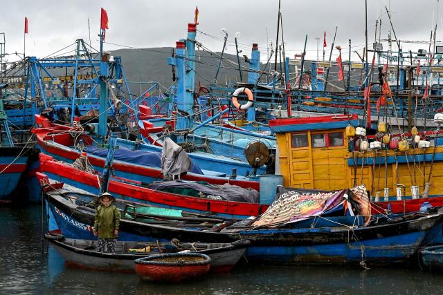 A woman looks on from a small boat as people prepare fishing vessels for the impact of Typhoon Kalmaegi at Quy Nhon fishing port in Gia Lai province in central Vietnam on November 6, 2025. The typhoon is forecast to make landfall in central Vietnam late on November 6, bringing waves as high as eight metres (26 feet) and powerful storm surges, according to the national weather bureau. (Photo by Nhac NGUYEN / AFP)