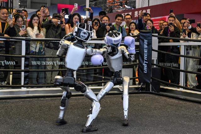 Remote-controlled robots by Unitree Robotics take part in a boxing match at the Unitree Robotics stand during the 8th International Import Expo (CIIE) in Shanghai on November 6, 2025. (Photo by Hector RETAMAL / AFP)