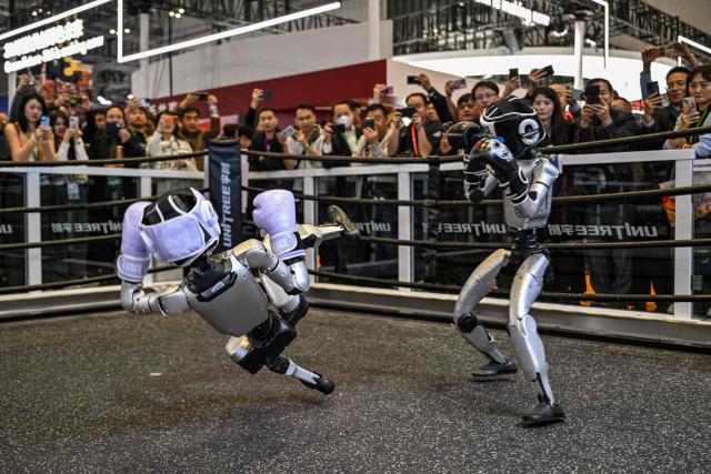 TOPSHOT - Remote-controlled robots by Unitree Robotics take part in a boxing match at the Unitree Robotics stand during the 8th International Import Expo (CIIE) in Shanghai on November 6, 2025. (Photo by Hector RETAMAL / AFP)