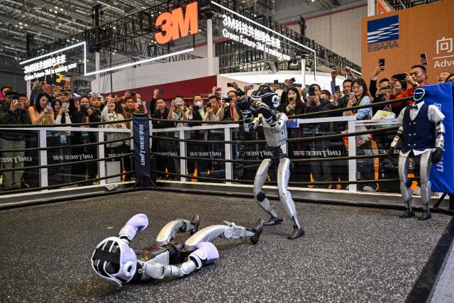 Remote-controlled robots by Unitree Robotics take part in a boxing match at the Unitree Robotics stand during the 8th International Import Expo (CIIE) in Shanghai on November 6, 2025. (Photo by Hector RETAMAL / AFP)