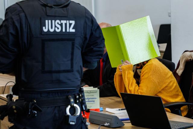 Defendant Susann E. hides behind a folder as she sits in the courtroom at the start of her trial as suspected supporter of the far-right extremist cell National Socialist Underground (NSU), on November 6, 2025 at the Higher Regional Court of Dresden. The National Socialist Underground (NSU) was a neo-Nazi cell behind a string of racist murders of mostly Turkish and Greek-born immigrants across Germany between 2000 and 2007. (Photo by JENS SCHLUETER / POOL / AFP)