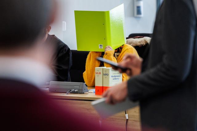Defendant Susann E. hides behind a folder as she sits in the courtroom at the start of her trial as suspected supporter of the far-right extremist cell National Socialist Underground (NSU), on November 6, 2025 at the Higher Regional Court of Dresden. The National Socialist Underground (NSU) was a neo-Nazi cell behind a string of racist murders of mostly Turkish and Greek-born immigrants across Germany between 2000 and 2007. (Photo by JENS SCHLUETER / POOL / AFP)