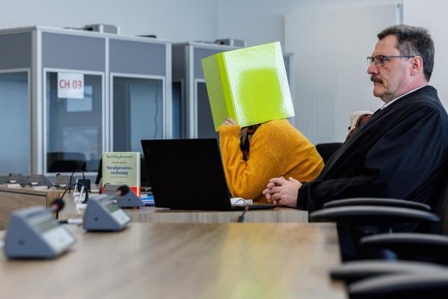 Defendant Susann E. hides behind a folder as she sits next to one of her lawyers Hendrik Koenig in the courtroom at the start of her trial as suspected supporter of the far-right extremist cell National Socialist Underground (NSU), on November 6, 2025 at the Higher Regional Court of Dresden. The National Socialist Underground (NSU) was a neo-Nazi cell behind a string of racist murders of mostly Turkish and Greek-born immigrants across Germany between 2000 and 2007. (Photo by JENS SCHLUETER / POOL / AFP)
