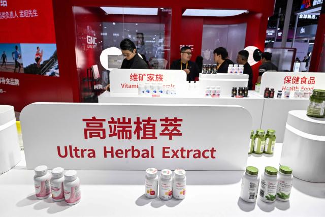 Visitors are seen at the General Nutrition Centers (GNC) stall during the 8th China International Import Expo (CIIE) in Shanghai on November 6, 2025. (Photo by Hector RETAMAL / AFP)